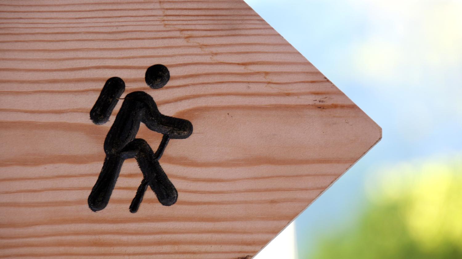 Holzwegweiser mit einem Wanderer