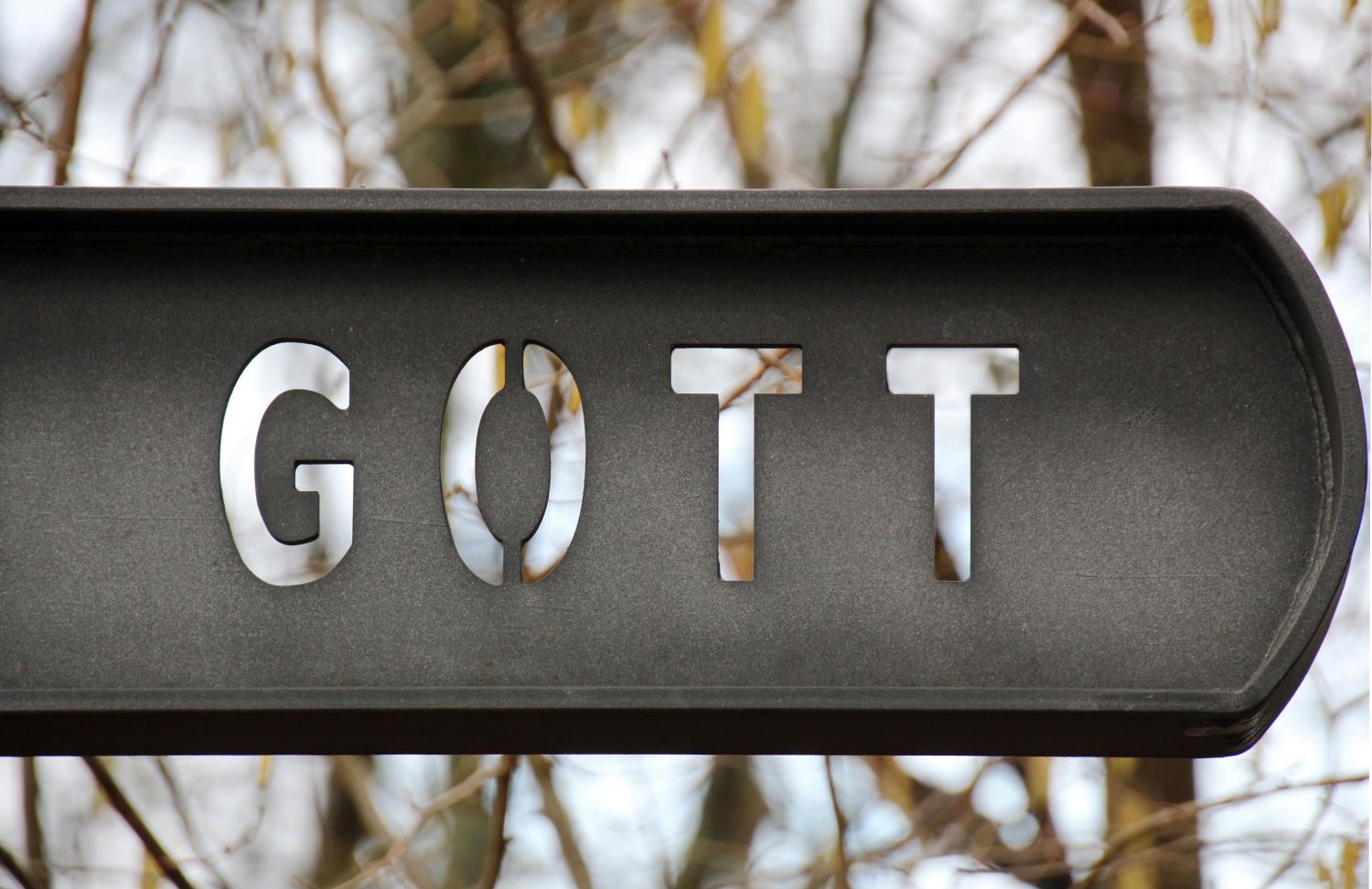 Metallschild mit dem Wort "GOTT" vor unscharfem Hintergrund